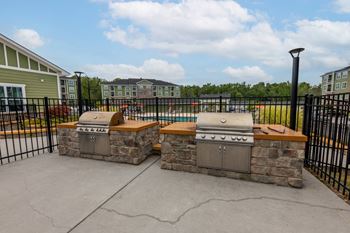 A stone fireplace with a black iron grate in front of a building.